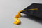 A black graduation cap with a gold tassel rests on a light gray surface.